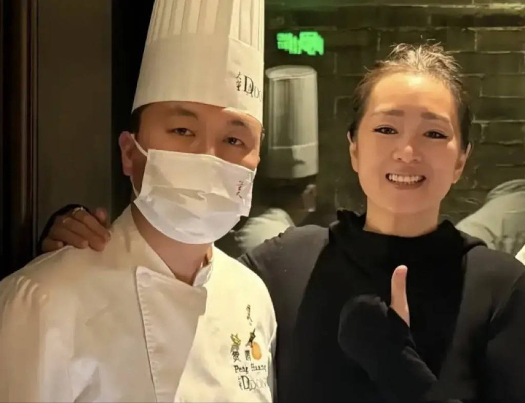 巩俐陪马克龙夫妇吃烤鸭，穿黑衣扎丸子头气场强，快六十岁还很美