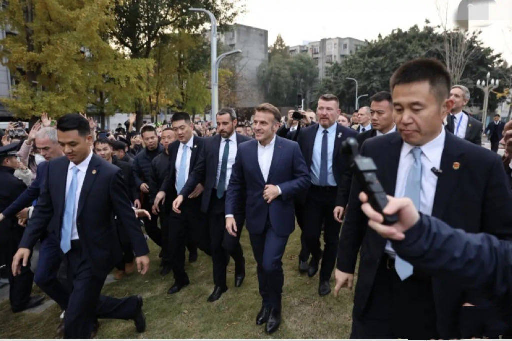 巩俐陪马克龙夫妇吃烤鸭，穿黑衣扎丸子头气场强，快六十岁还很美