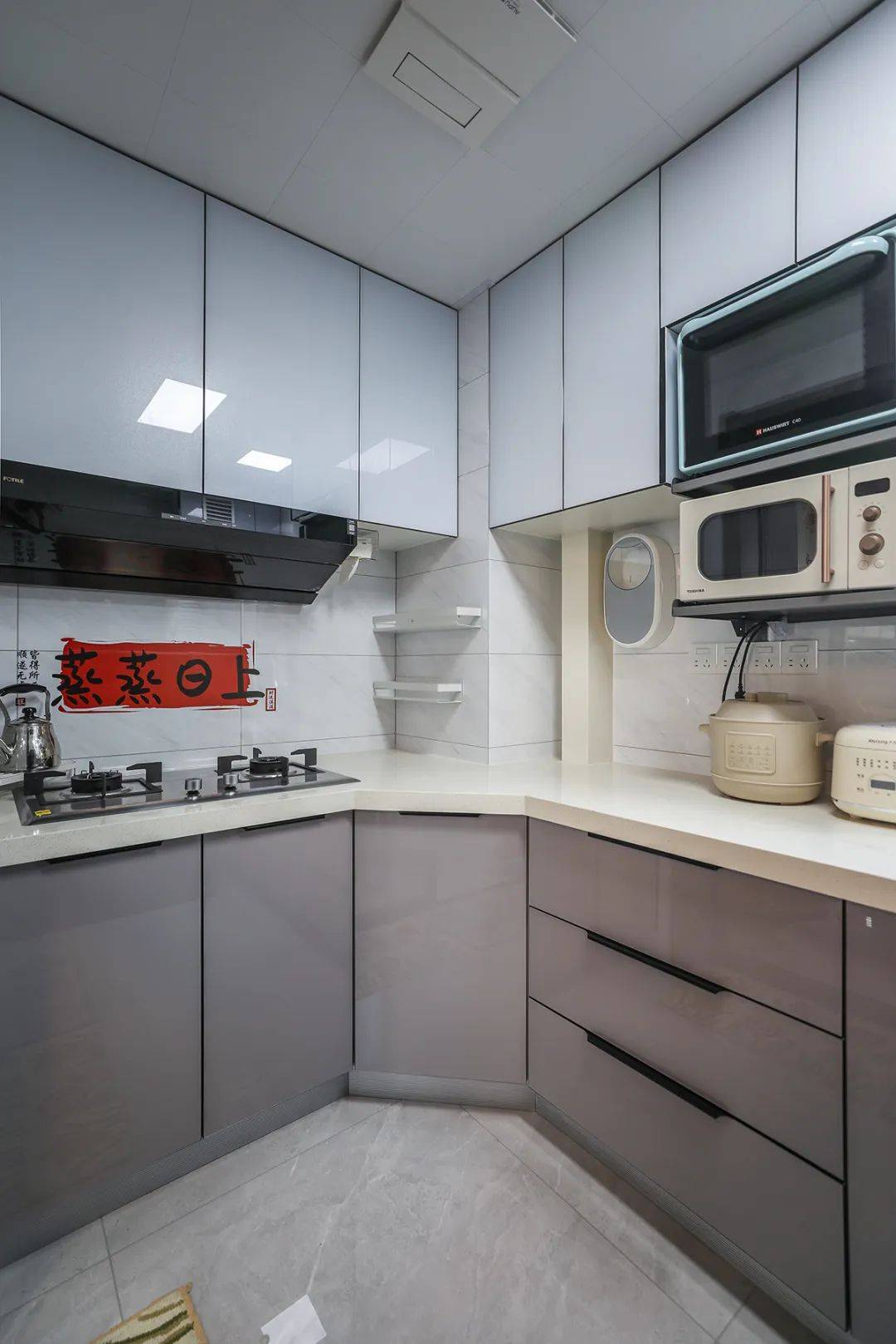 该套房子厨房空间很大,l型三面橱柜,另外冰箱边上也有操作台,颜色简洁