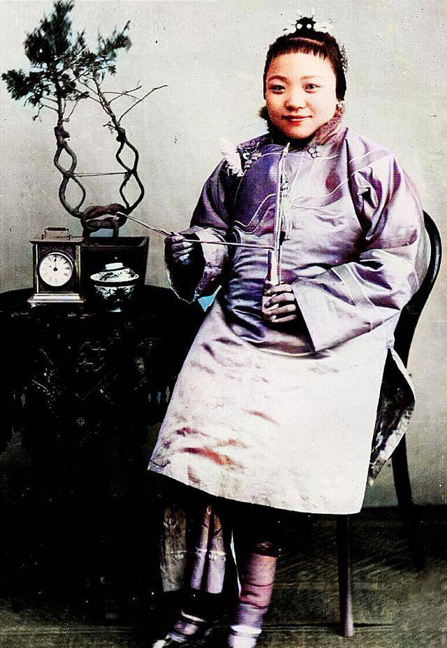 图中的女子正拿着纸媒子作势点燃手中的水烟斗.