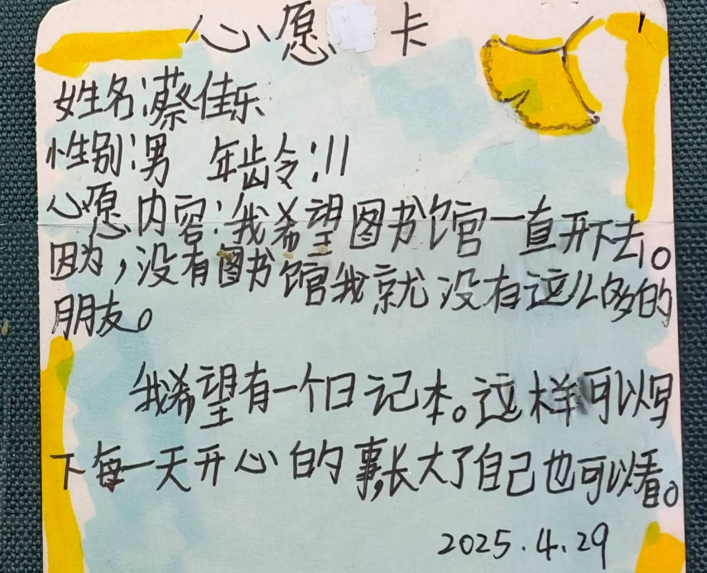 书屋围墙上有一块心愿墙,贴着一些孩子写的心愿卡,其中一张上面稚嫩的