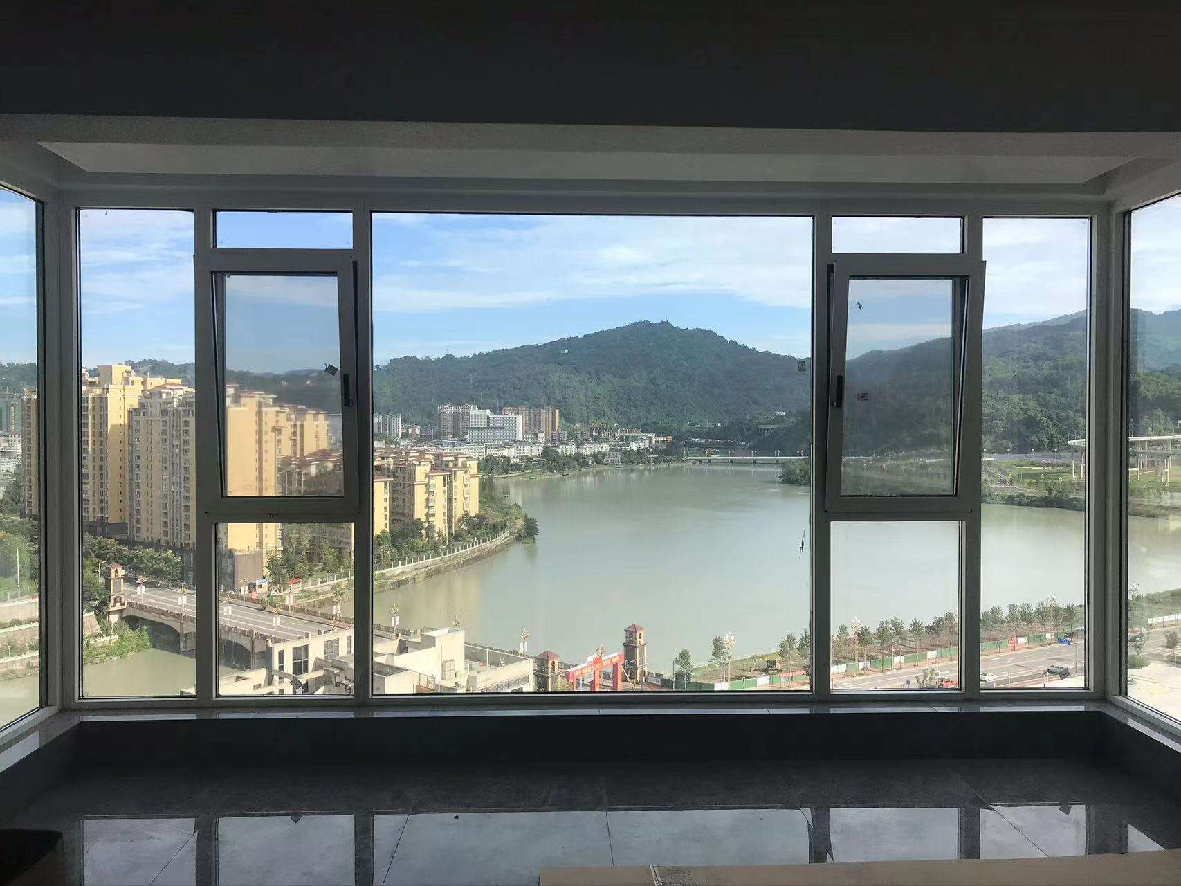高层住宅室内视角，展示宽大的灰色断桥铝落地窗系统。中间采用大面积固定玻璃，两侧配置开启扇，最大化引入自然光线。窗外拥有开阔的江景、青山与城市建筑群，视野极佳。深