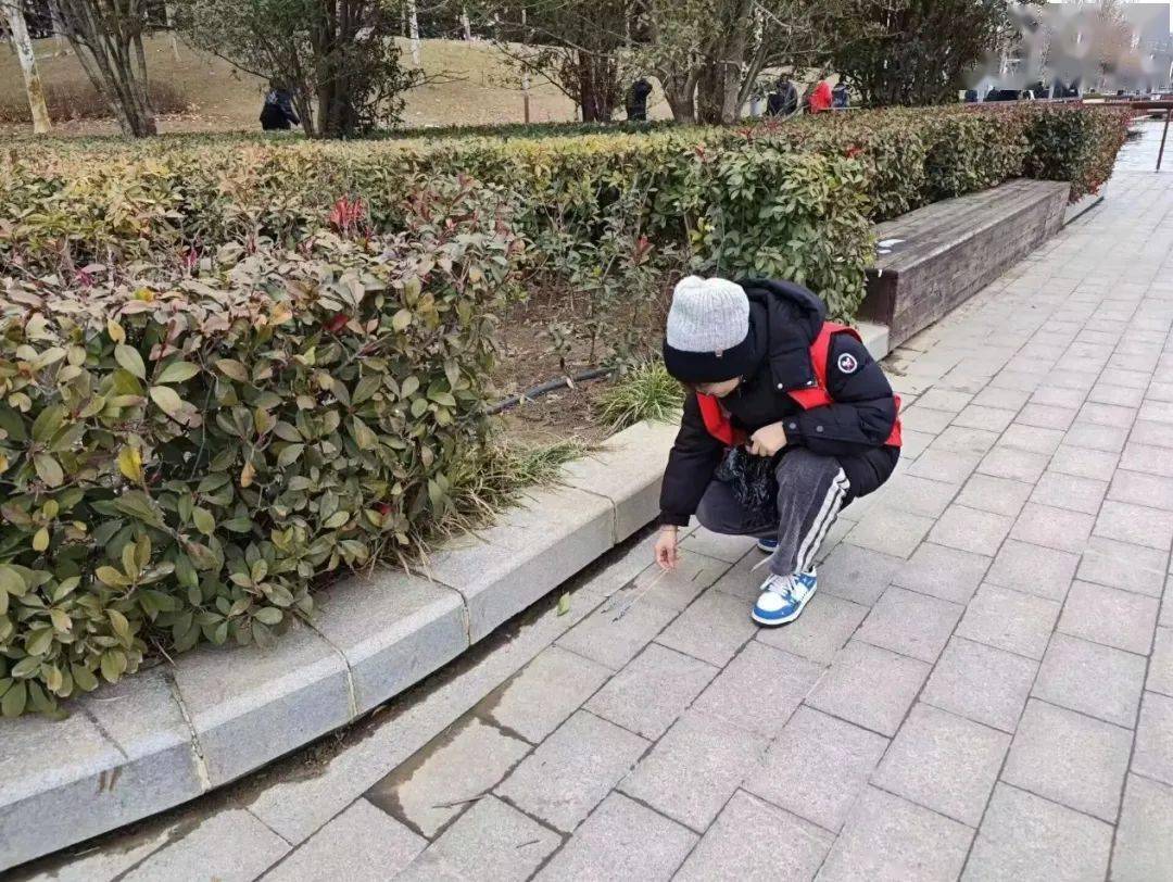 在公园里,团队成员积极捡拾地上的垃圾,并通过随机采访路人的方式
