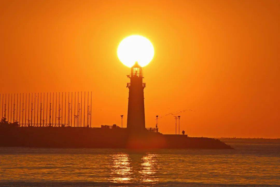 破晓时分,一轮红日从海平面缓缓升起,晨光洒在黄金海岸上,海岸泛着