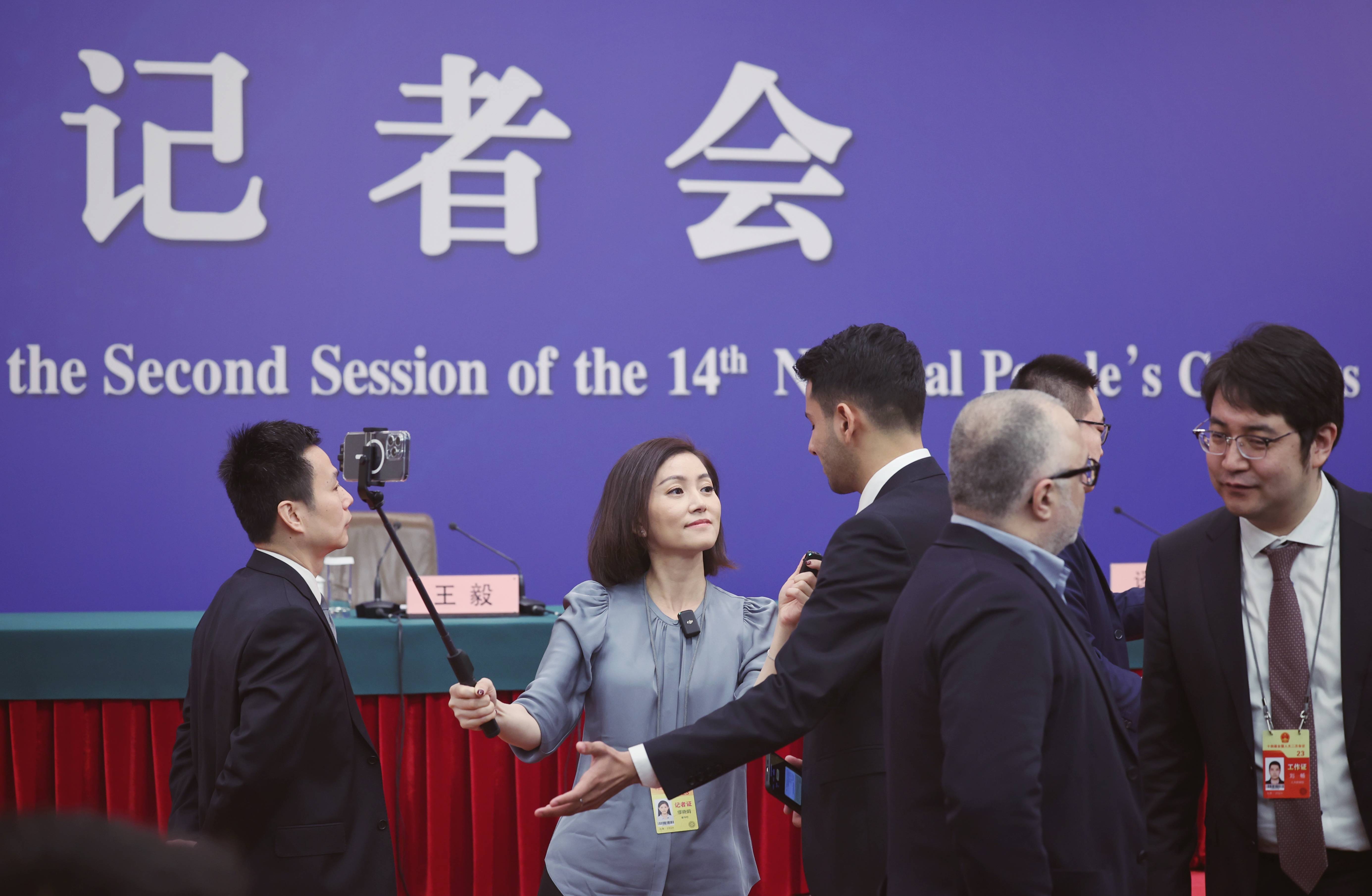 3月5日,十四届全国人大二次会议在北京人民大会堂开幕,一位女记者戴着