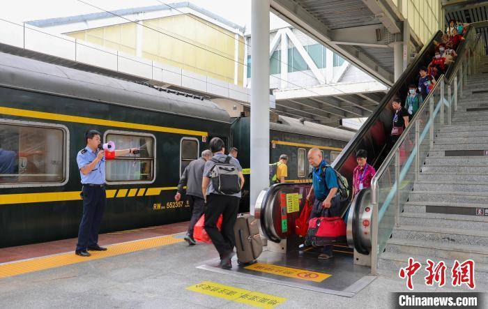 5月22日,桂林北站客运工作人员在电梯口为"银发"旅游专列的旅客提供