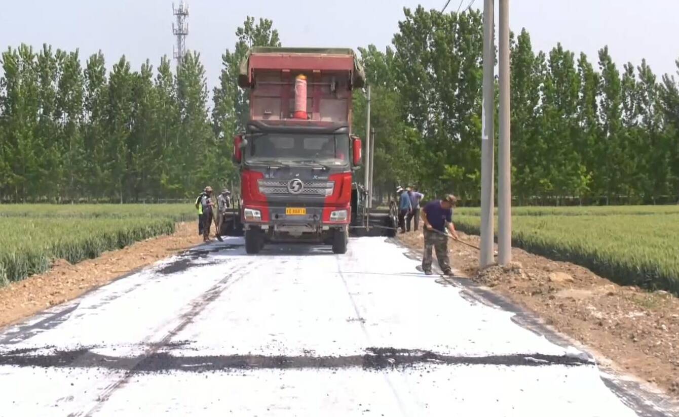 记者在姜庄镇王干坝村口看到,摊铺机,压路机和运材料的大车正来回穿梭