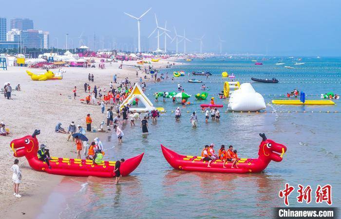 7月13日,山东威海荣成市一处海水浴场,游客们体验各种水上娱乐项目