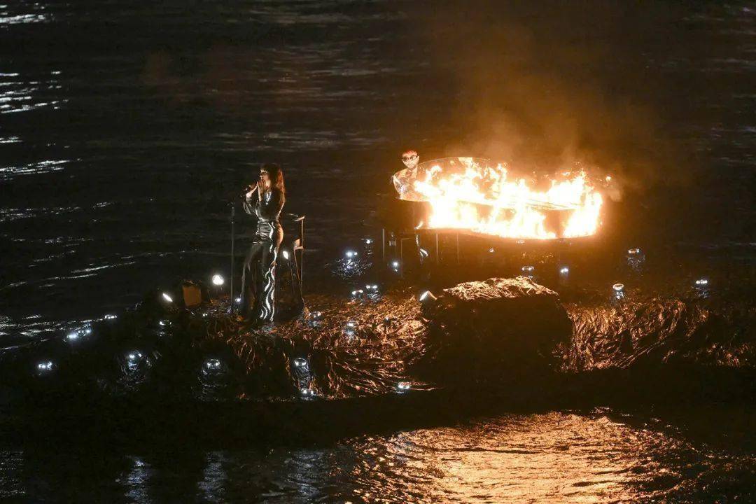漂流的木筏上,音乐家在雨中弹奏熊熊燃烧的钢琴,唱响列侬名作