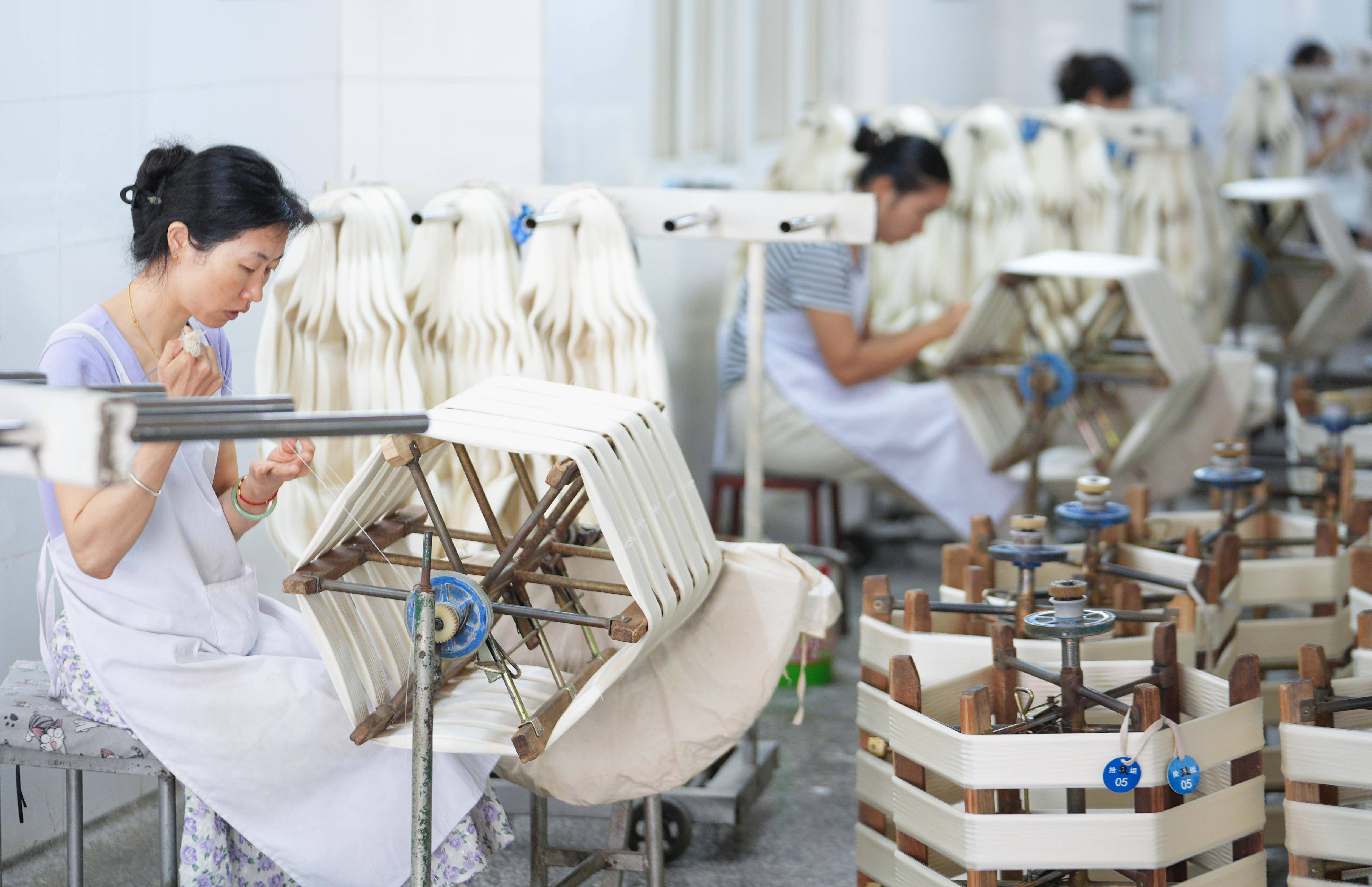 集中发展区南丝路集团银鸿丝业有限公司,工人们在缫丝车间精加工生丝