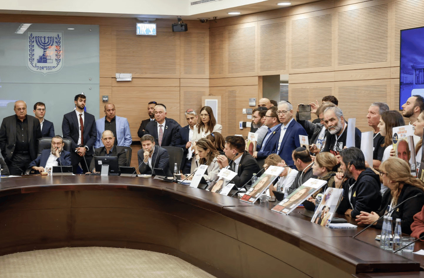 满怀怒火、哭喊恳求！以色列被扣押人员家属手持照片挤进会场谴责以财长