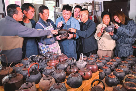 第三代传承人张有喜(左三)在为大家介绍铁壶的制作工艺。泥模雕刻是制